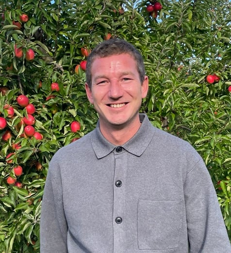 Jack Houston PR and Marketing Manager in front of an apple orchard